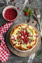 Homemade tender curd casserole with juicy berries cranberries on a gray stone background with forks and branches of berries. Top View.
