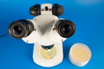 Scientific microscope and petri dishes for scientific research on blue background