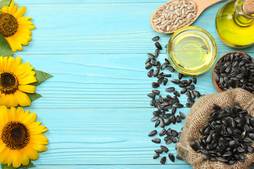 Sunflower oil, seeds and flower on blue wooden background. top view with copy space