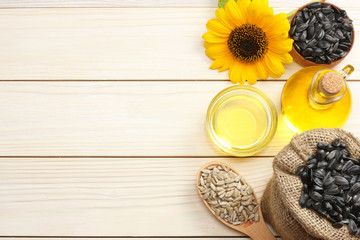 Sunflower oil, seeds and flower on white wooden background. top view with copy space