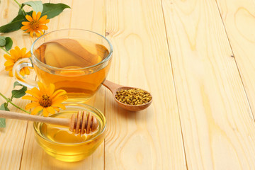Honeycomb with honey dipper and honey on light wooden table