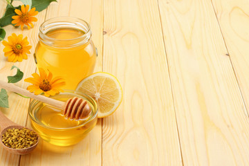 Honeycomb with honey dipper and honey on light wooden table