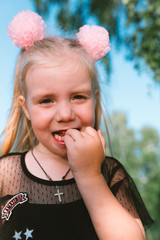 Portrait of child girl with blonde hair and blue eyes in the forest