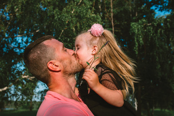 Happy Father's Day! Child girl and her father having fun together, playing and kissing in the park, outdoors