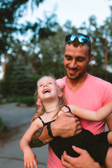 Happy Father's Day! Child girl and her father having fun together, playing and kissing in the park, outdoors