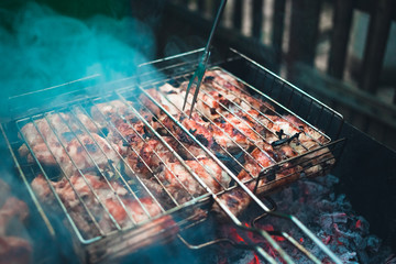 Grilled kebab cooking on metal skewers (grill). Roasted meat cooked at barbecue with smoke. Close up BBQ fresh pork meat chop slices. Traditional eastern dish, shish kebab.
