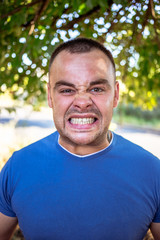 Young man in a blue T-shirt with a chipped tooth