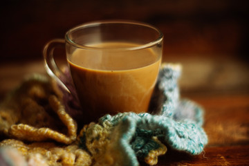 Cup of coffee wrapped in scarf on books background