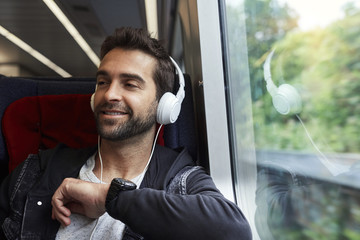 Dude with phones on train, looking away and smiling