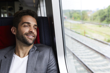 Guy relaxing in seat on train journey, smiling