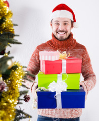 Man on holiday in hat with gifts near Christmas tree