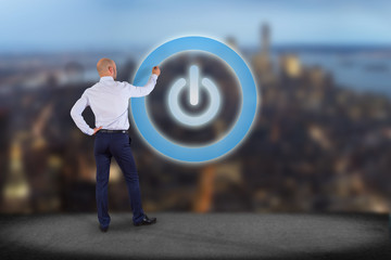 Businessman in front of a wall with Power button symbol displayed on a futuristic interface - Technology and energy concept
