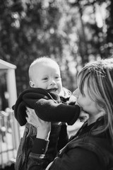 Portrait of mother who hug her joyful baby boy. Outdoors healthy child activity, active lifestyle and having fun on family summer vacation with son at the playground.