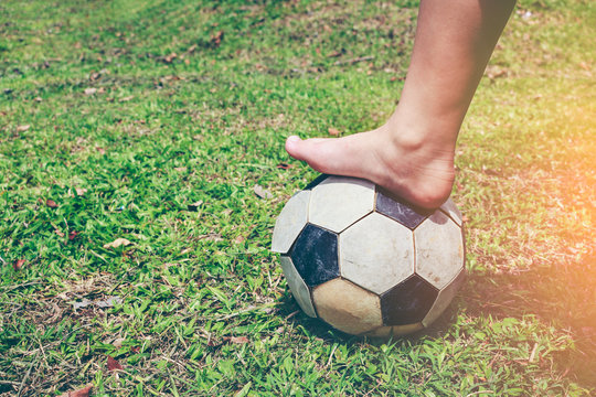 Barefoot football player tread on the soccer ball. Healthy lifestyle concept.