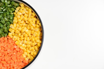 Three color vegetable platter: diced orange carrot, green bean and yellow corn kernel, on white background with negative space.