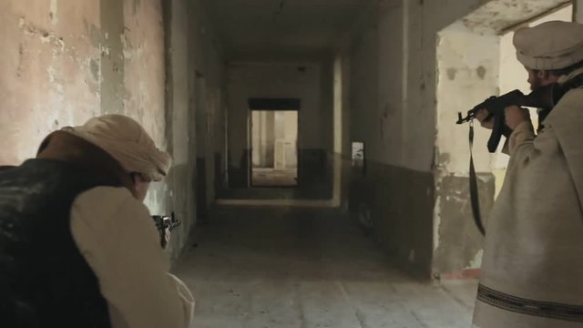 Two men shoot enemies in the corridor of the abandoned building