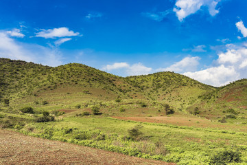 Landscape View of mountains and green fields with blue sky