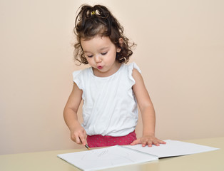 Naklejka premium Cute young girl drawing with a pencil in the notebook