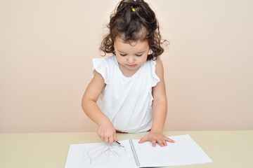 Naklejka premium Cute young girl drawing with a pencil in the notebook