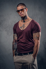 Tattooed male over grey background in a studio.