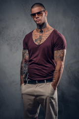 Tattooed male over grey background in a studio.