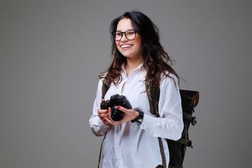 Female holds digital photo camera and a tripod.