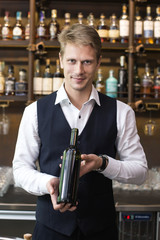 Handsome sommelier man promoting bottle of wine in restaurant, Man present Wine to Customer, Man with Sommelier Concept.