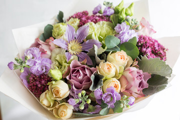 Close-up floral composition with roses and mix flowers on a light background.