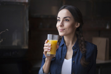 Young girl drinks orange juice from glass