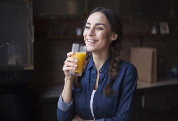 Happy woman with juice in the morning at kitchen