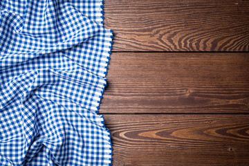 Blue checkered tablecloth on an old wooden table. Close up