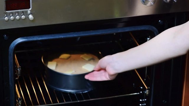 Woman's hand puts a potato casserole in the oven