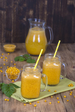 Yellow sea-buckthorn juice in a glass and ripe yellow sea buckthorn on a vintage wooden table. Bio healthy food and drink. Organic diet.