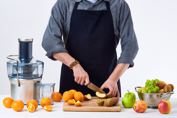 Anonymous man wearing an apron, preparing fresh fruit juice using modern electric juicer, healthy lifestyle detox concept on white background