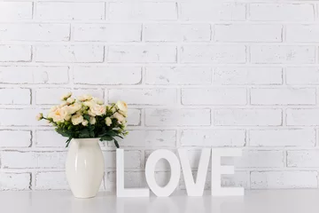 Foto op Plexiglas wooden letters forming word LOVE and flowers over white brick wall © Di Studio