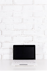 modern laptop on the table over white brick wall