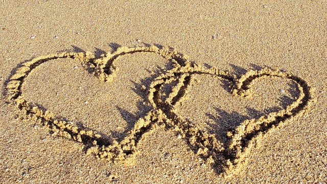 	The drawing heart on sand. Heart is washed away by a sea wave.