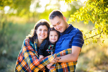 Fototapeta premium happy family walking in an autumn park at sunset, hiding in a padded hug and smiling