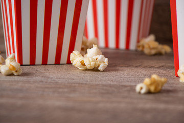 Popcorn in red and white cardboard on wooden table.