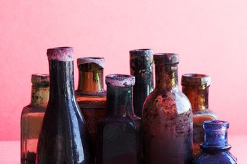 Retro design bottles macro view. Colorful dirty glass flacon set. Pink background, shallow depth of...