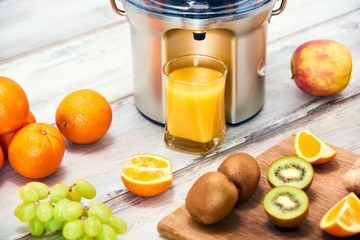Modern electric juicer, various fruit and glass of freshly made juice, healthy lifestyle detox...