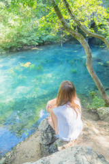 Fototapeta premium Young woman sitting near the beautiful lake in nature.