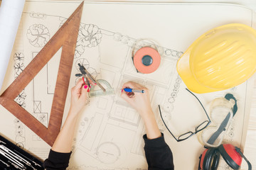 Architect drawing on a blueprint with a compass and ruler.
