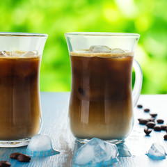 Iced coffee in a glass with cream over summer background