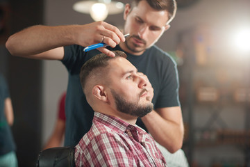 Handsome young man getting a new hairstyle at the local barbershop. 