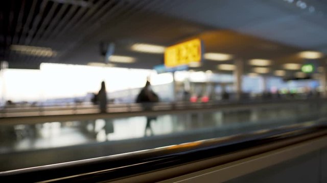 Defocused escalator at airport, passengers rushing to gate, transportation