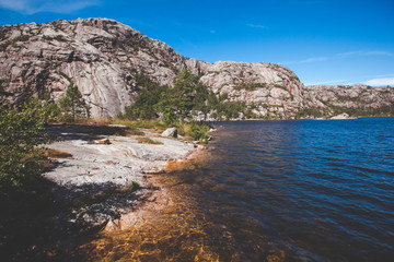 Beautiful Photo Norway, Scandinavia. Beautiful landscape on the lake shore middle of the stone mountains. blue sky for publication in magazine or advertisement
