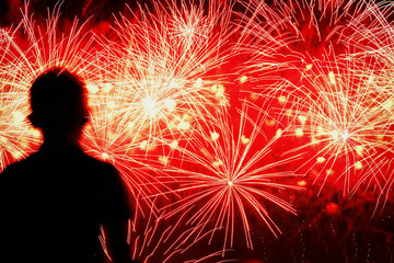 Fototapeta na wymiar Unrecognizable silhouette of a child with his back to us, which looks spectacular show Fireworks. Festive background with place for text