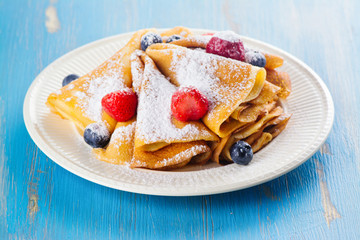 Crepes with jam, berries and sugar powder. Homemade pancakes, delicious breakfast