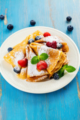 Crepes with jam, berries and sugar powder. Homemade pancakes, delicious breakfast